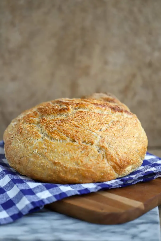 fresh bread on a blue checked cloth on a wooden cutting board