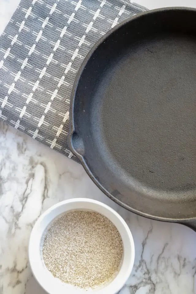 Clean cast iron skillet with dirty salt used to clean it off to the side