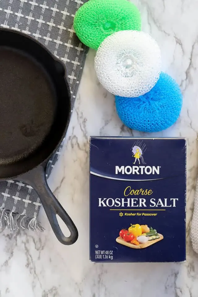 Cast iron pan with kosher salt and nylon scrub brush