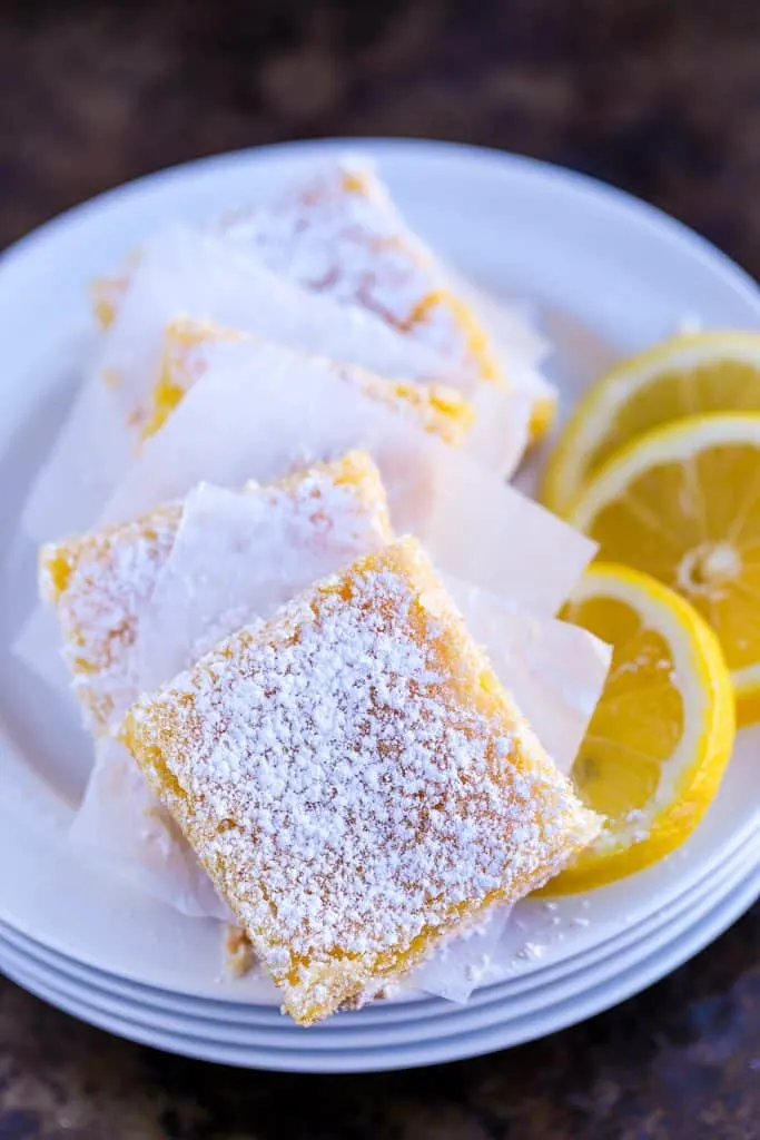 five Lemon squares on a plate with lemon slices