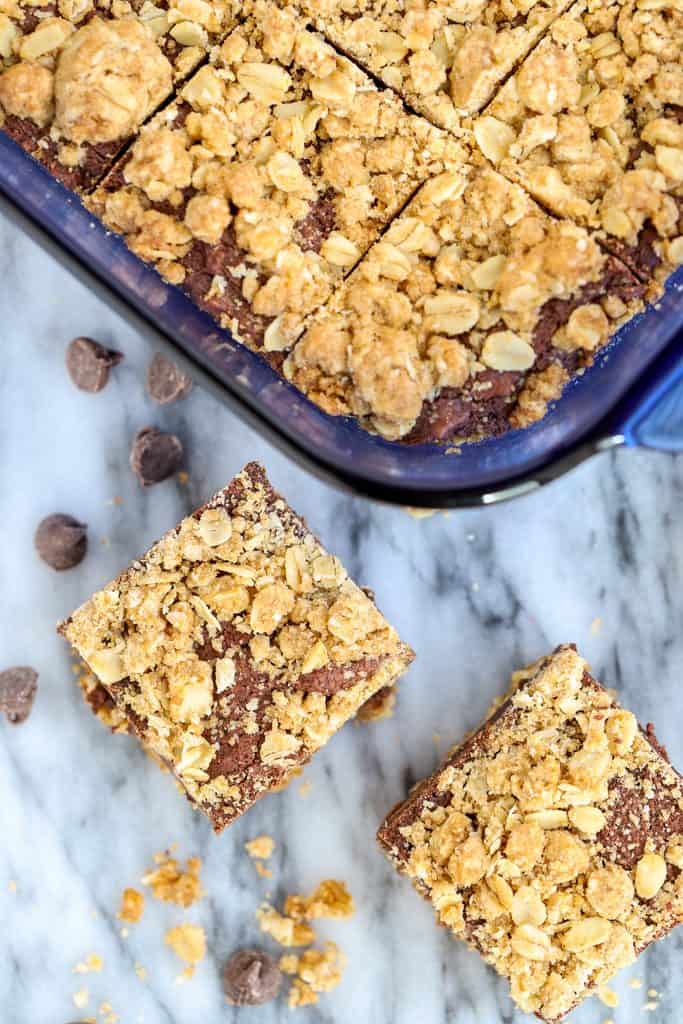 Overhead photo of oatmeal fudge bars with two individual squares next to the blue pan filled with more bars