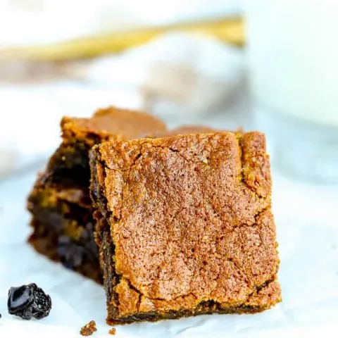 A stack of hermit bars with one serving square in front with raisins on the white plate