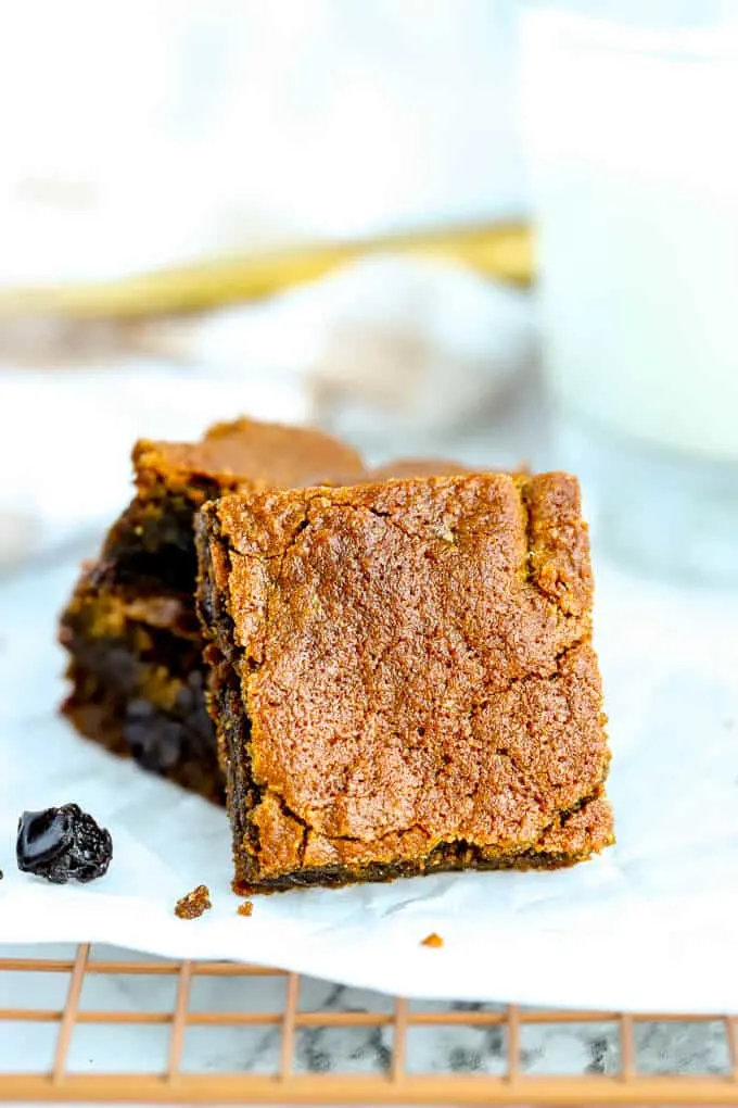 A stack of hermit bars with one serving square in front with raisins on the white plate