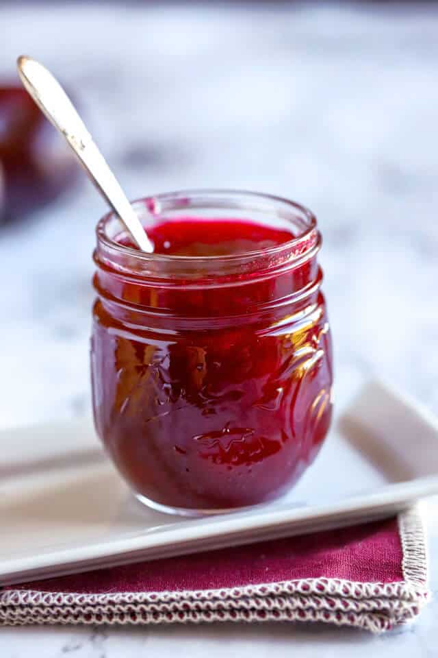 Plum jam in lovely mason jar on a white tray with burgundy napkin