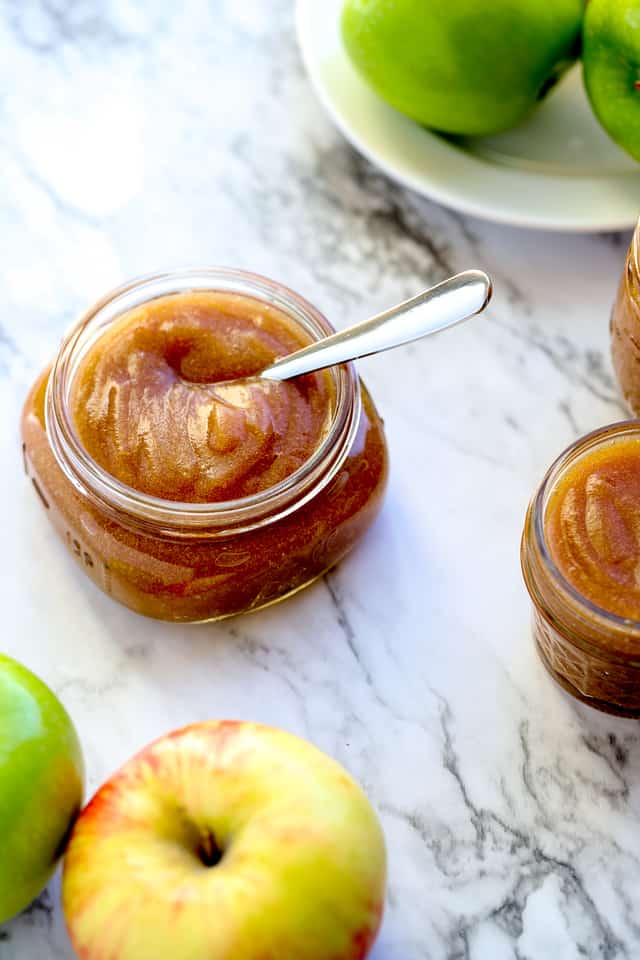 Overhead photo of crock pot apple butter in a small jar on a marble countertop