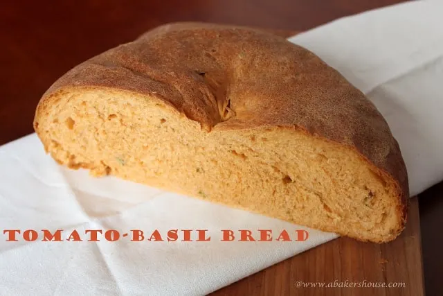 homemade tomato basil bread loaf cut in half on a white napkin