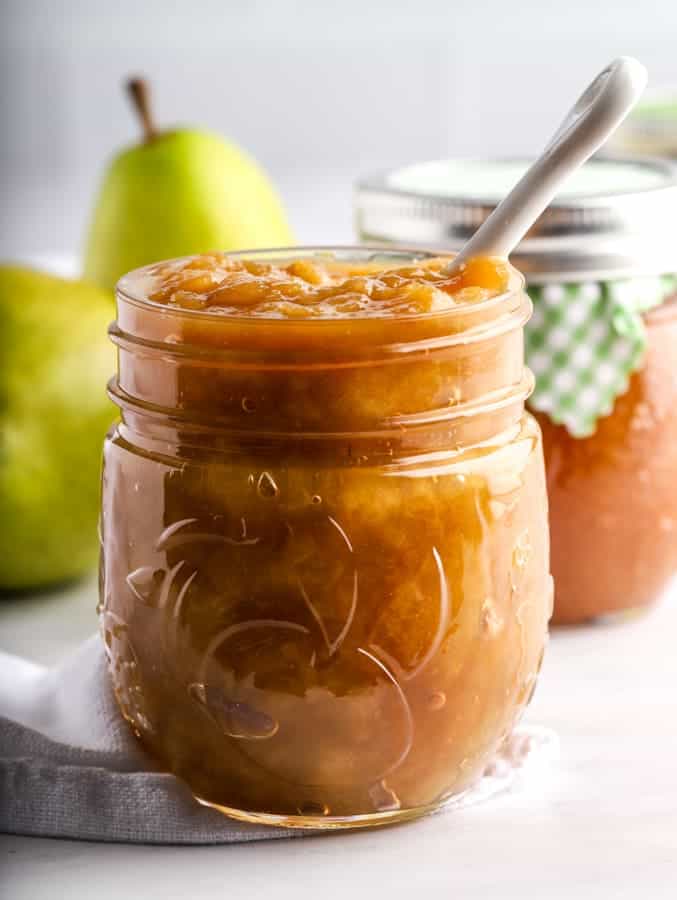 Pear ginger jam in a mason jar with white spoon