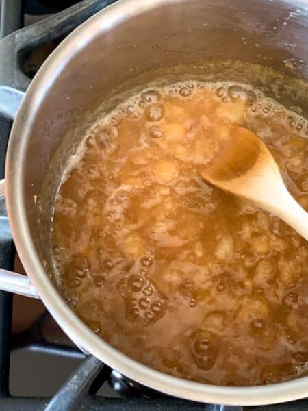 pear jam simmering on stovetop with wooden spoon stirring the jam