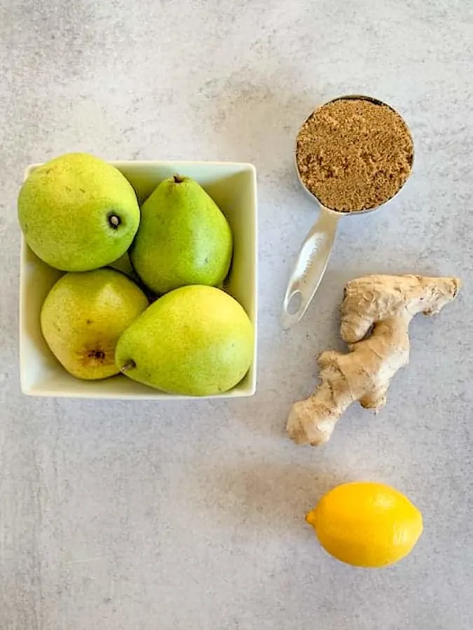Ingredients for pear ginger jam of pears, sugar, ginger and lemon on a concrete tabletop