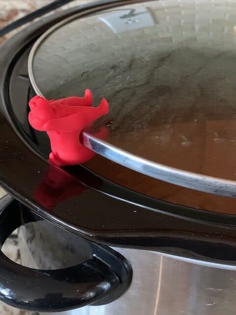Silicone lid lifter in dog shape on edge of crock pot lid