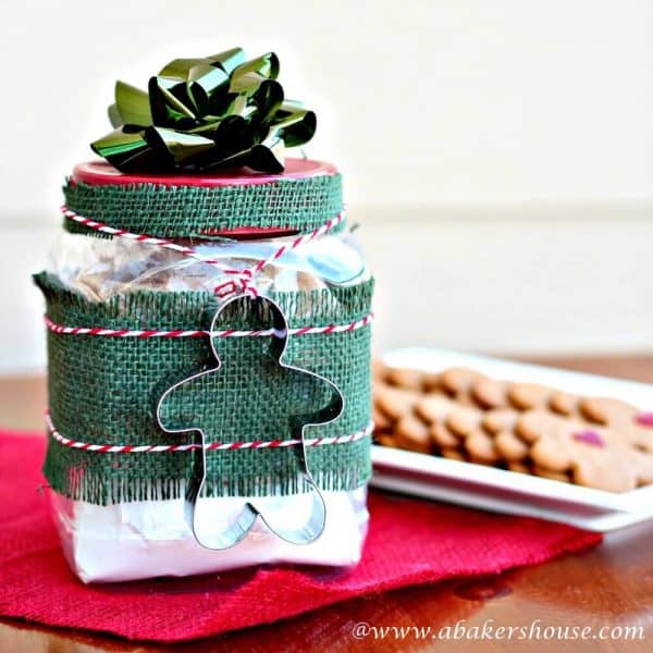 Gifts in a jar of gingerbread cookie mix with cookie cutter and baked cookies in background