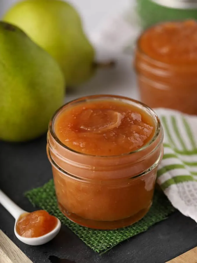 Pear butter in small mason jar on cutting board with pears