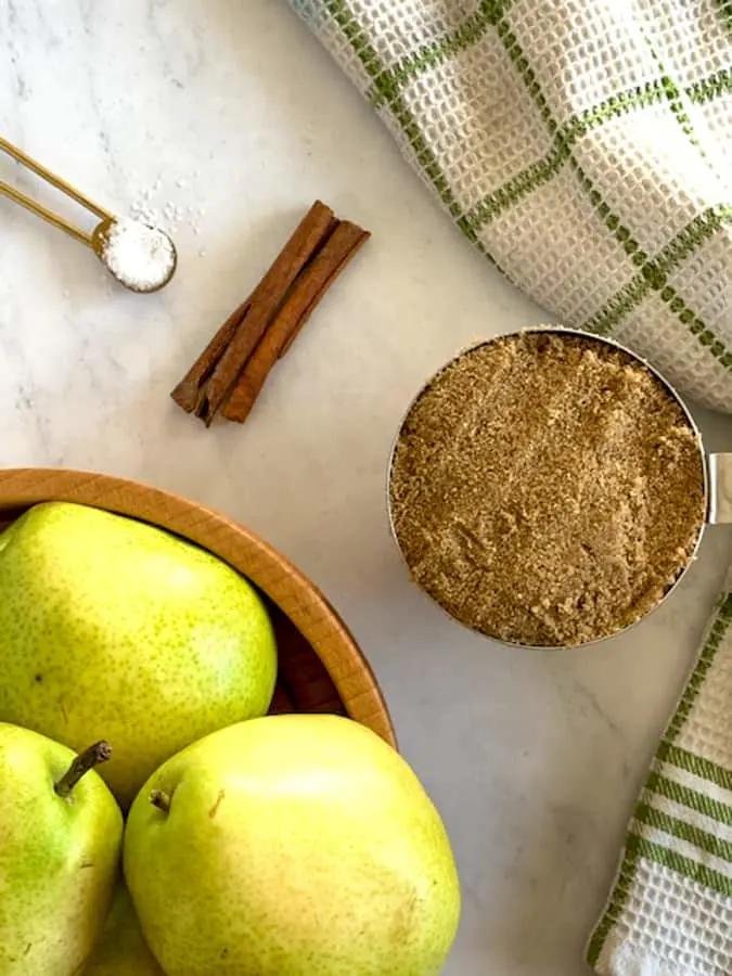 Ingredients of pear butter of pears, cinnamon, brown sugar and salt on marble board
