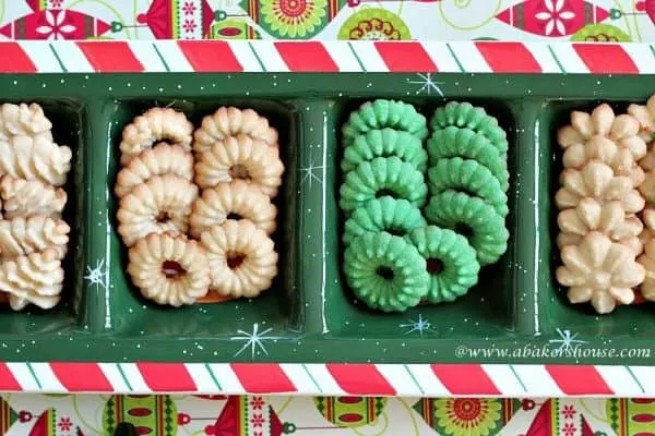 Christmas Spritz Cookies in the shape of trees and wreaths on a holiday serving tray