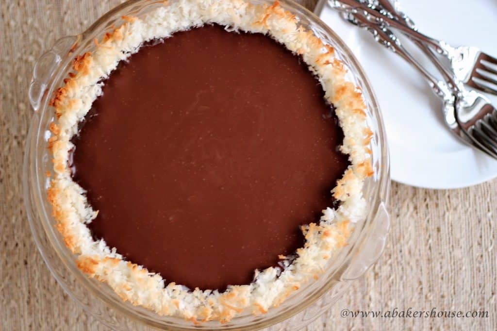 Overhead photo of coconut chocolate pie next to a white plate with forks