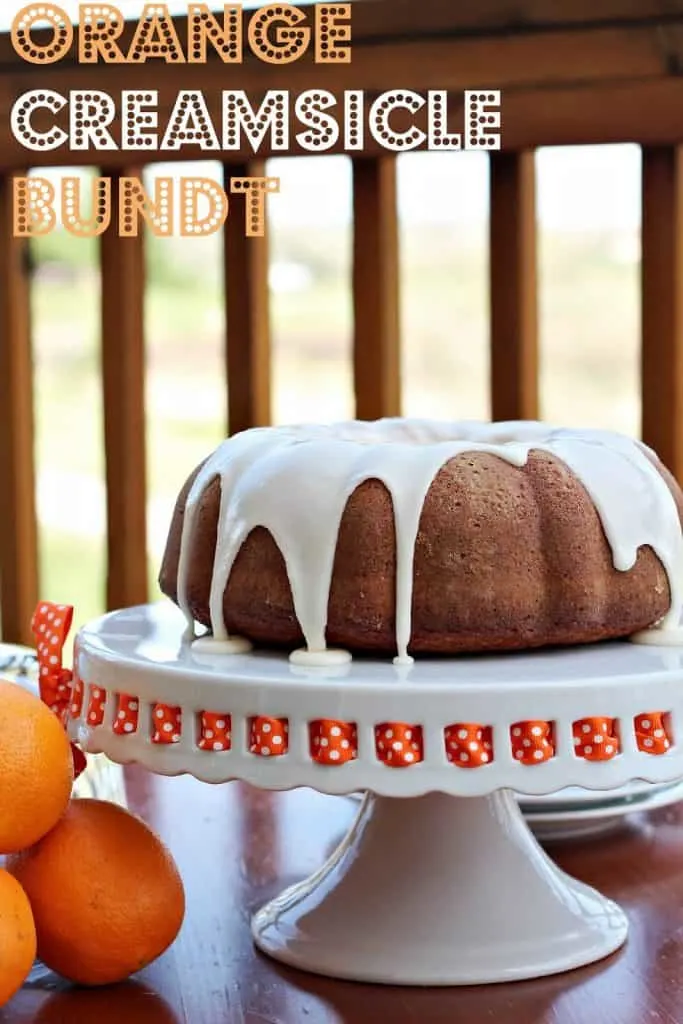 orange Creamsicle Bundt Cake with vanilla glaze on a white cake stand