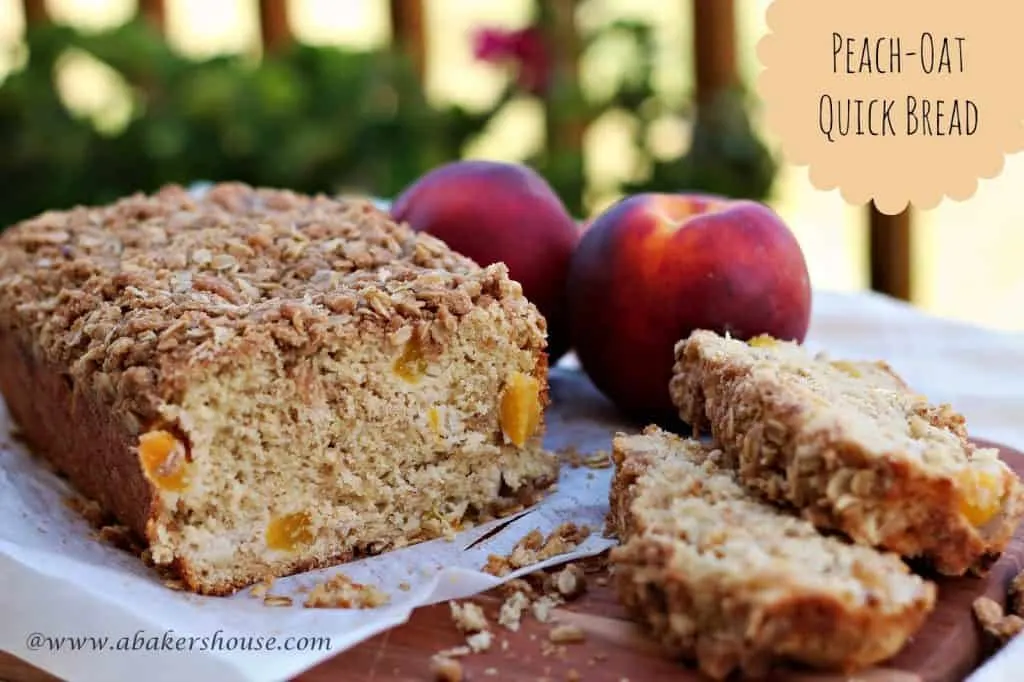 Peach oat quick bread with streusel topping sliced next to fresh peaches