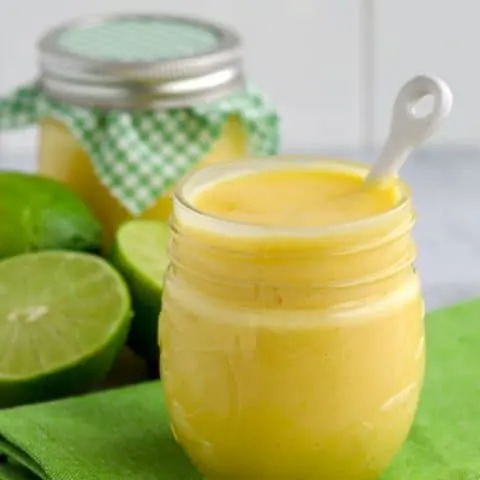 Two jars of lime curd with limes on green napkin
