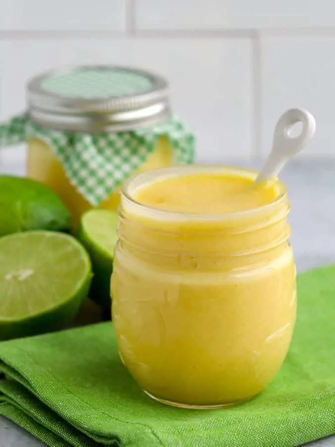 Two jars of lime curd with limes on green napkin