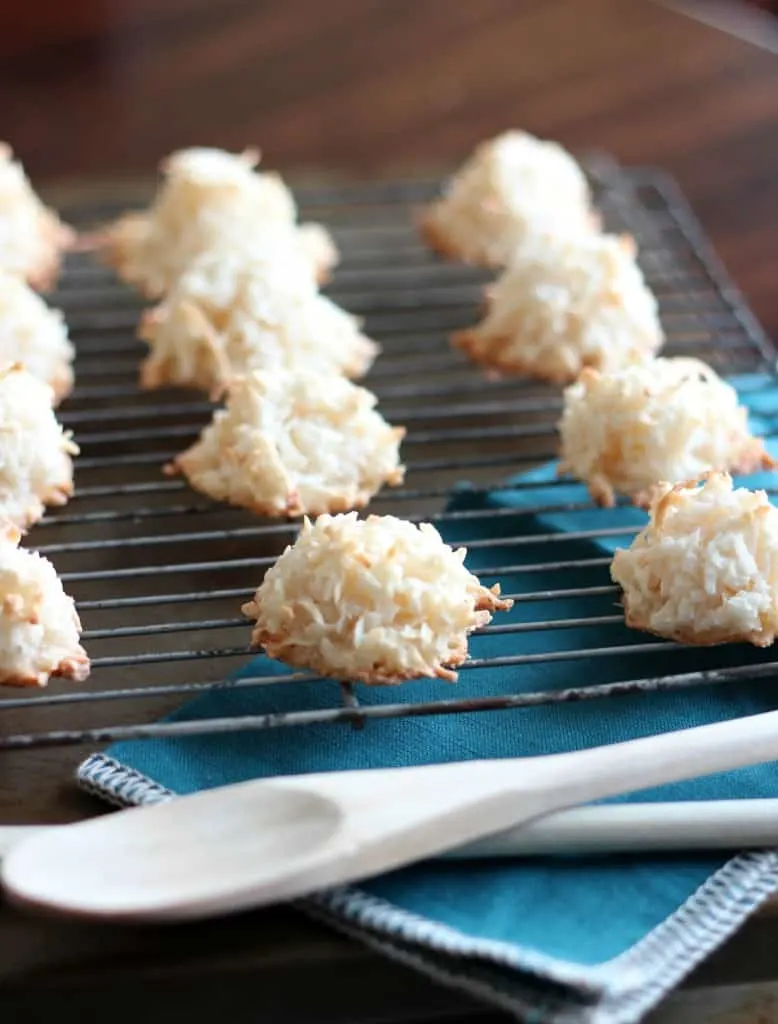 a dozen coconut macaroons on wire cooling rack and with white and blue napkins underneath