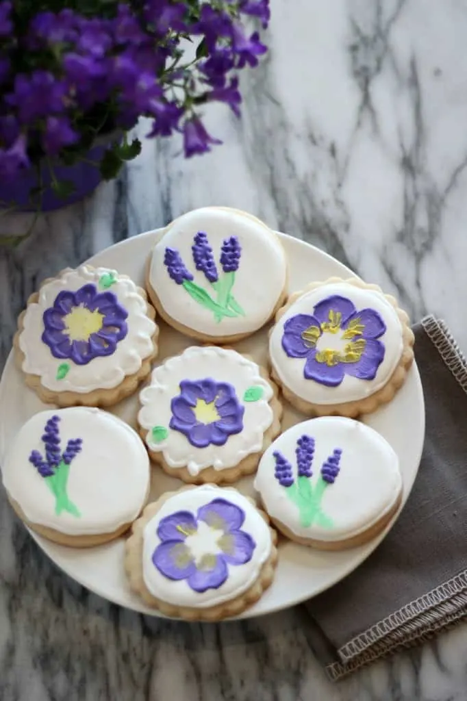 Sugar cookies decorated with painted flowers all on a plate