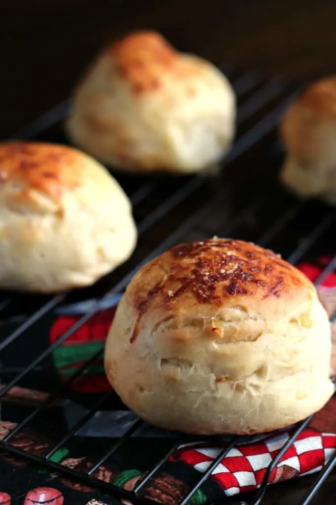 close up of one onion roll on a wire rack with other rolls in background