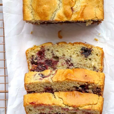 Overhead photo of gluten free cherry quick bread with three slices on white parchment