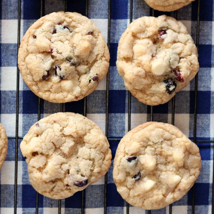 red white and blue cookies with dried berries and white chocolate on a wire cooling rack and checked blue and white napkin