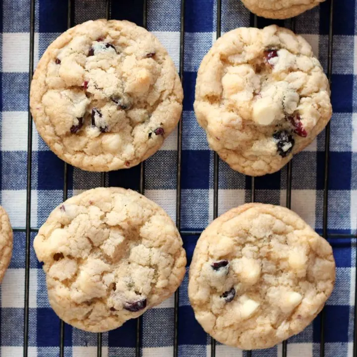 red white and blue cookies with dried berries and white chocolate on a wire cooling rack and checked blue and white napkin