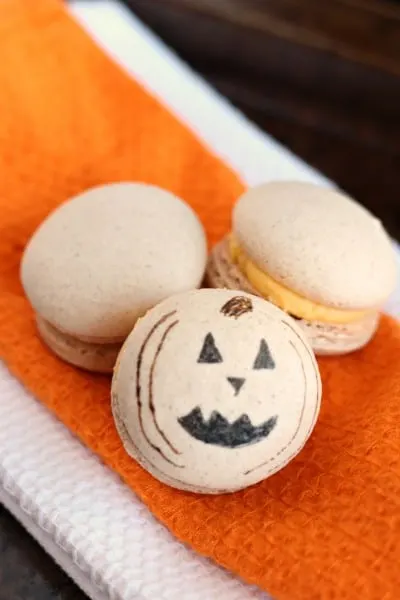 pumpkin macarons with drawn on jack o lantern face