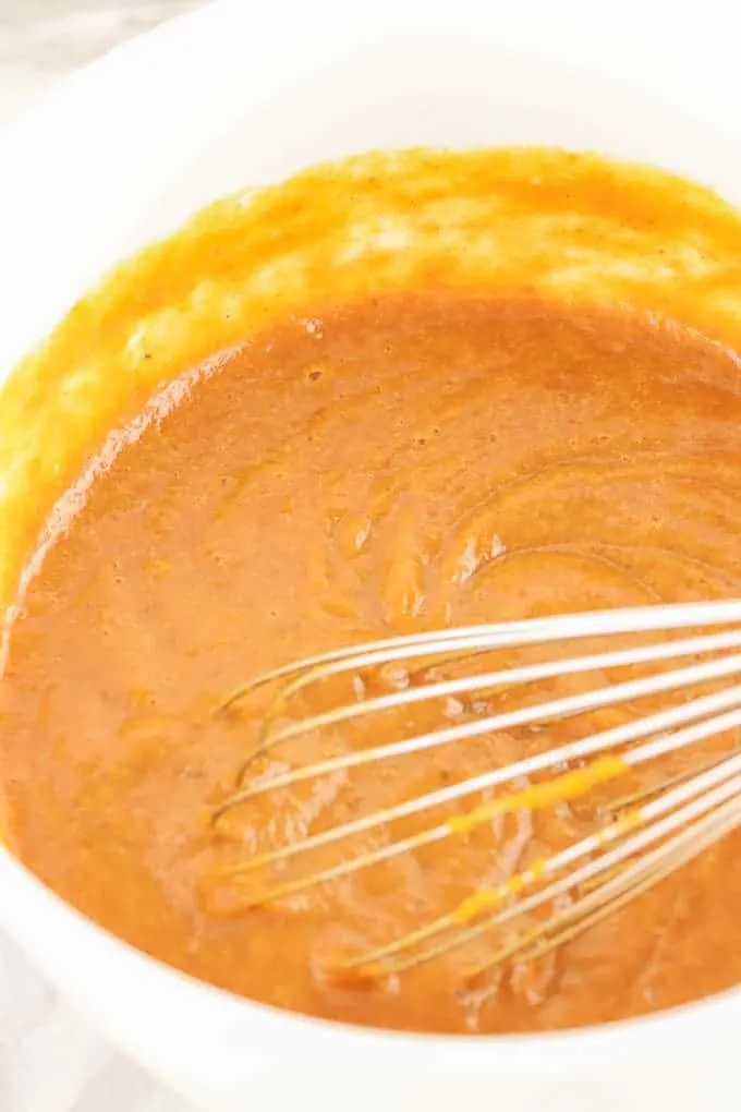 Whisk in a white bowl of ingredients with pumpkin puree for gluten free pumpkin pie filling