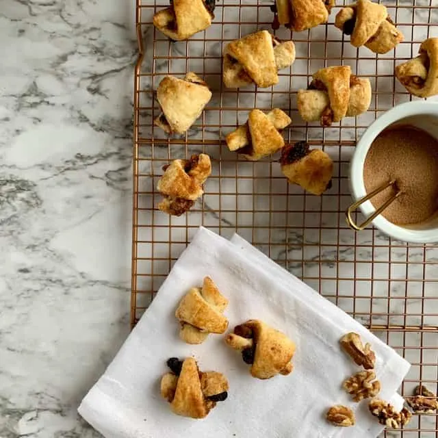 Baked rugelach on white napkin and more on cooling rack