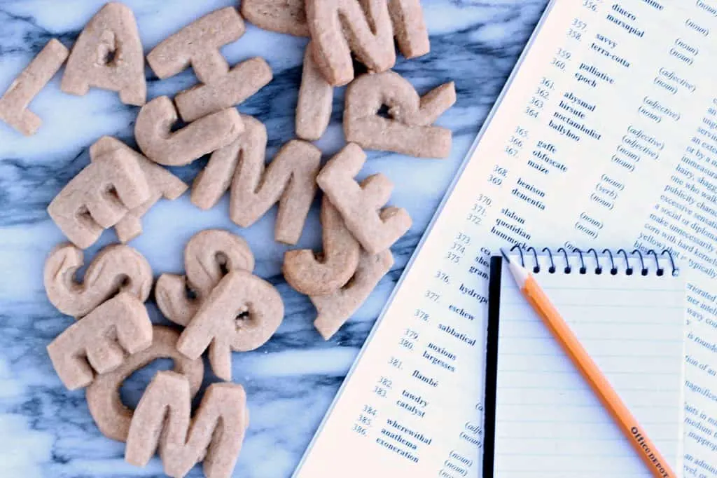 Alphabet letter cookies on a marble board with list of spelling bee words aside