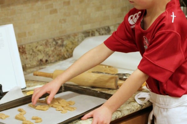 little hands forming letter cookies placed on a baking sheet