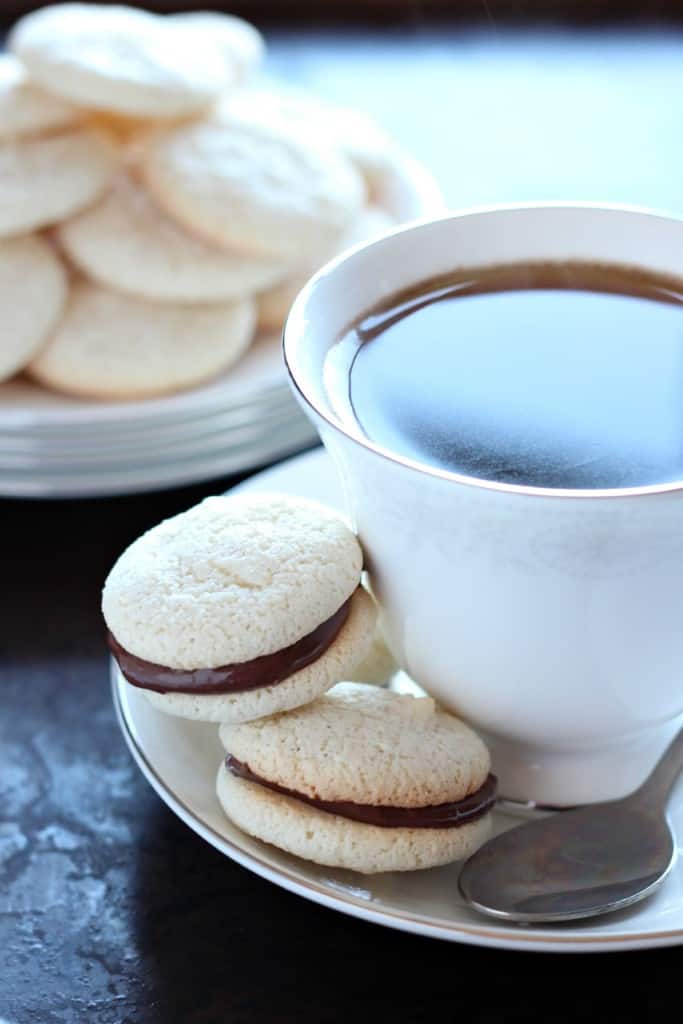 amaretti biscuits sandwiched with nutella next to a cup of tea