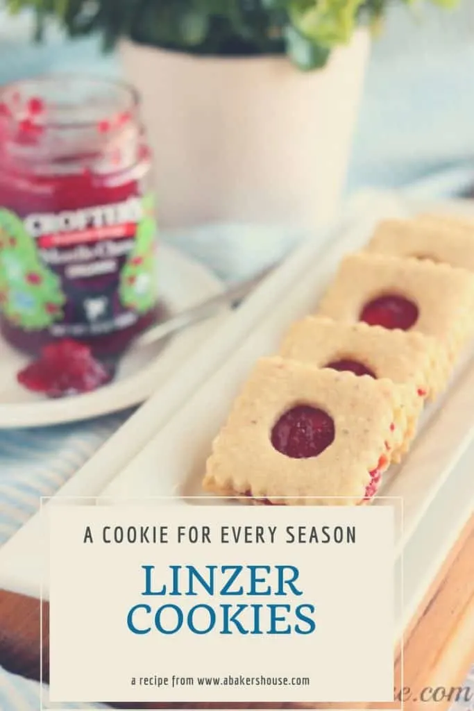 Linzer Cookies on white rectangular platter with jar of jam