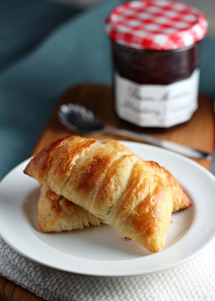 homemade danish pastry on white plate with jam jar behind