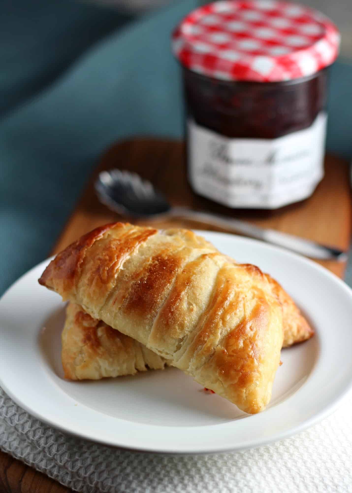 homemade danish pastry on white plate with jam jar behind