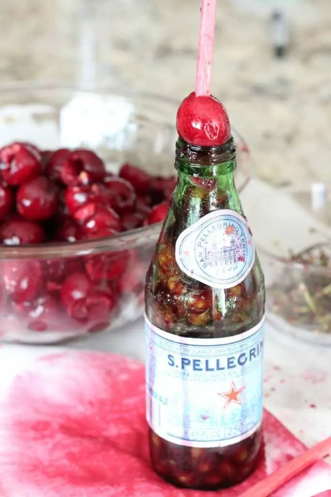 cherry set on top of glass bottle with chopstick used to take out the pit