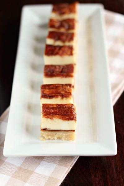 seven layered churros cheesecake bars lined up on white plate