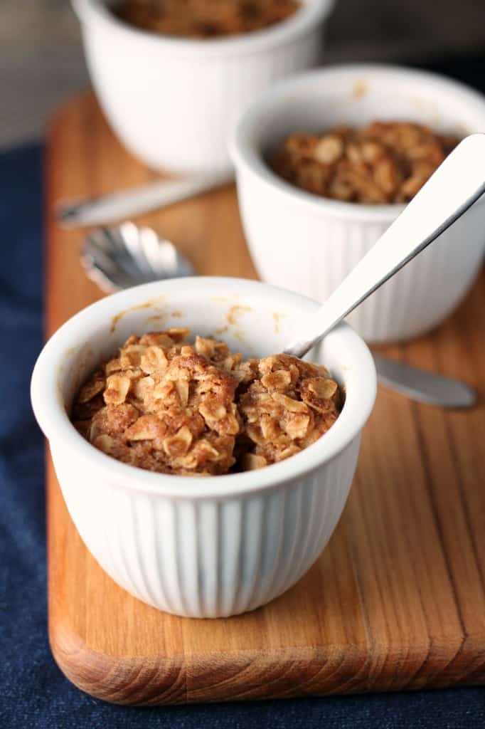 Three Individual Maple Apple Crisps in white bowls on wood cutting board