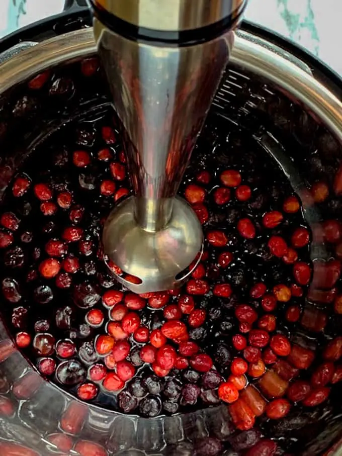 Immersion blender purees the berries for wojapi to make a Native American berry sauce from frozen berries