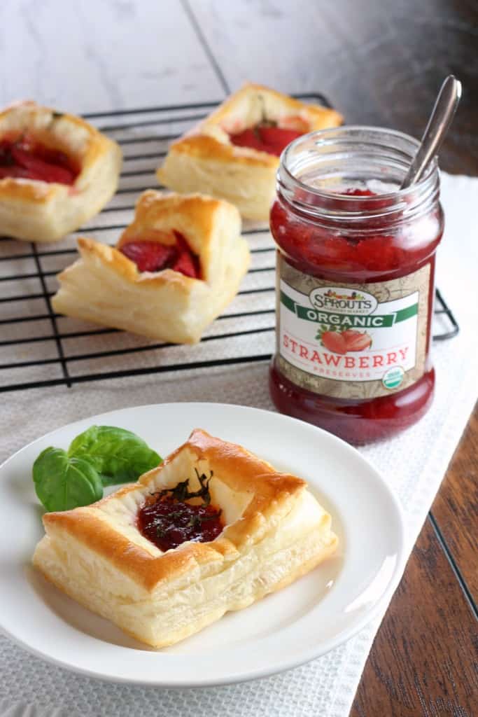 Puff pastry strawberry preserves tarts on white plate with jar of strawberry jam