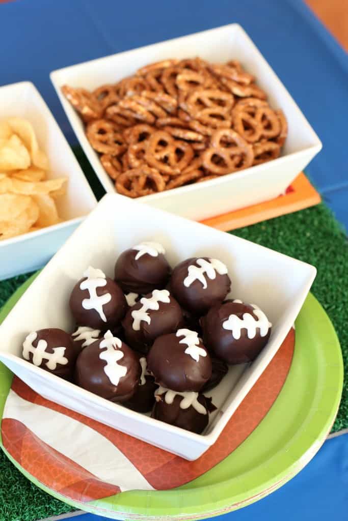 Football Cookie Balls in white square bowls with pretzels and chips