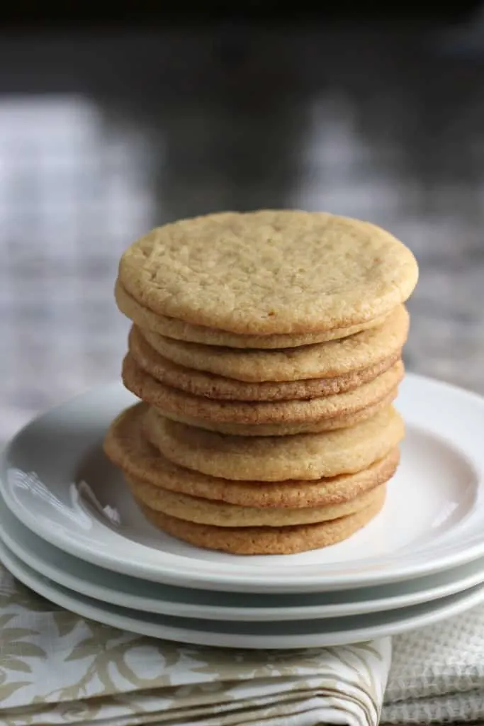 Tall stack of maple cookies on a white plate with a patterned napkin underneath