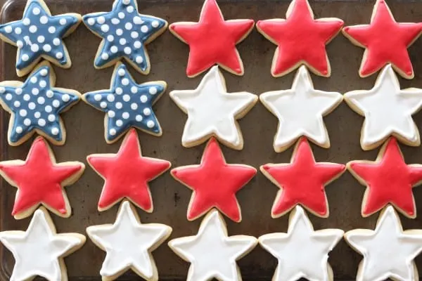 patriotic cookies with red, white, and blue stars lined up in a flag pattern on a baking tray