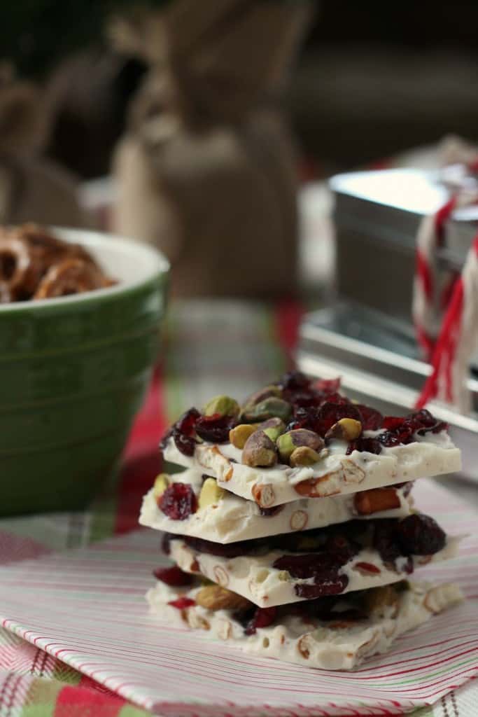 white chocolate bark candy broken into pieces stacked with pistachios and dried cherries