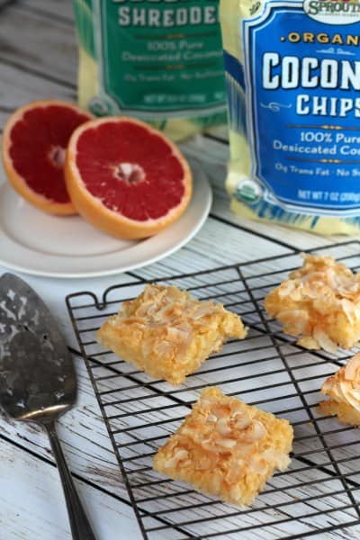 Coconut-grapefruit squares on wire rack with cut grapefruit