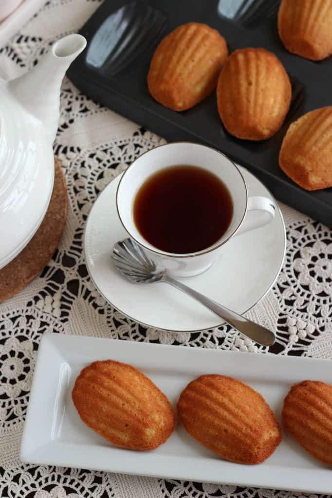 vanilla honey madeleines in black baking pan on a lace cloth