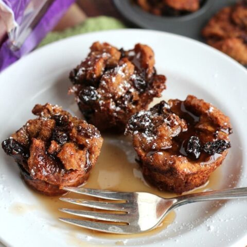 French toast muffins with raisins on white plate with syrup and fork